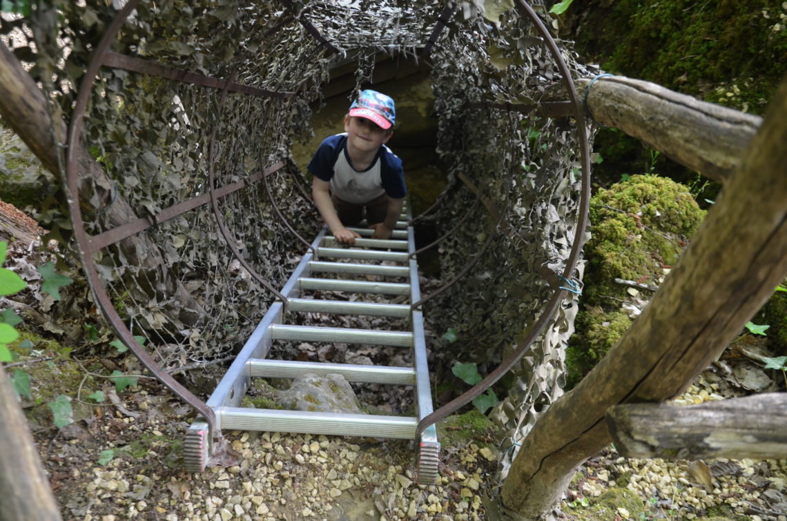 Yuri climbing up a ladder, surrounded with camouflage. Part of the adventure path for children.