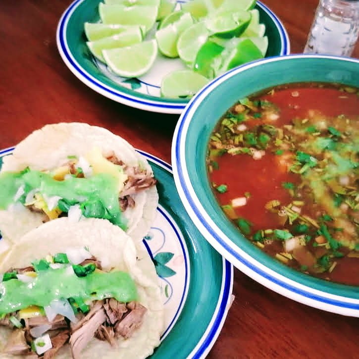 Birria. 3 plates with lime slices, a dip and meat.