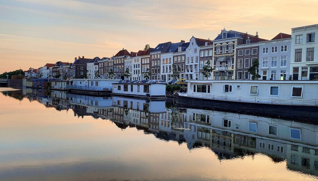 Middelburg by Offbeat Escapades, a row of houses on a river with house boats in front of the houses