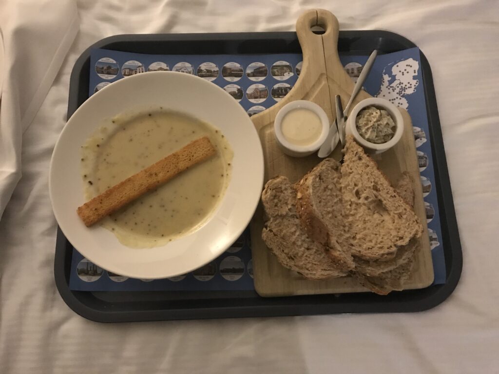 Mustard soup and bread with dips, served on a small serving plate. Mustard soup in a deep plate, served with a large crouton. On the right a wooden board with slices of bread and dips