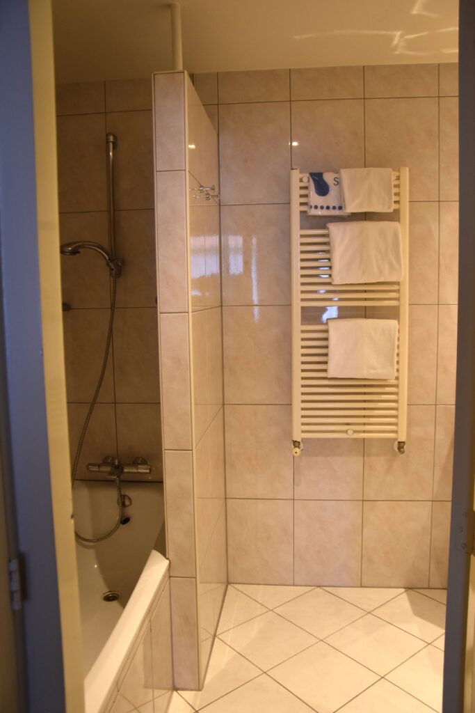The bathroom, the bath on the left, a heater at the back to the wall