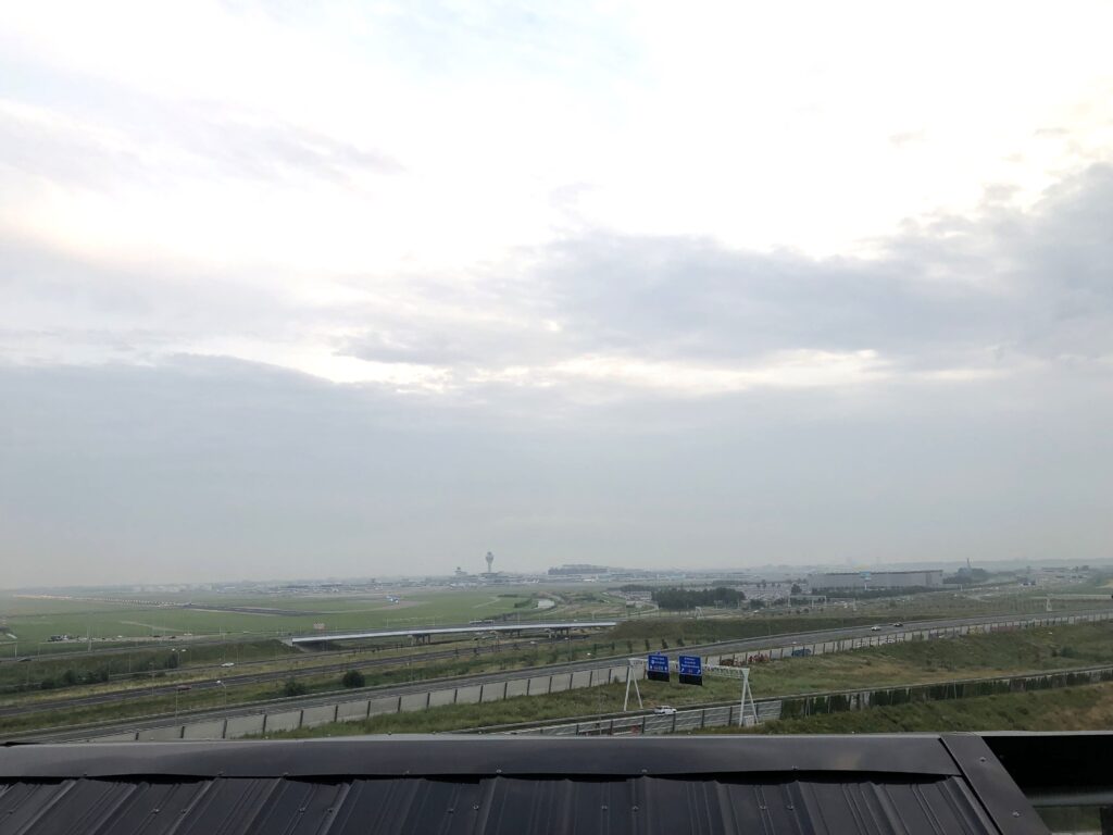 Schiphol Airport as seen from the roof terrace, a highway in between, with a clouded sky above